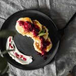 Tasty pancakes topped with fresh berry sauce on a ceramic plate, perfect for a gourmet breakfast.